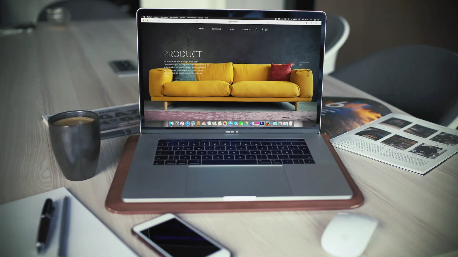A laptop showing an online furniture store on a tidy desk beside a coffee mug and a phone