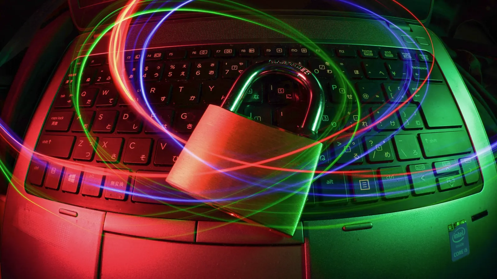 A padlock resting on a laptop keyboard, surrounded by red and green light trails