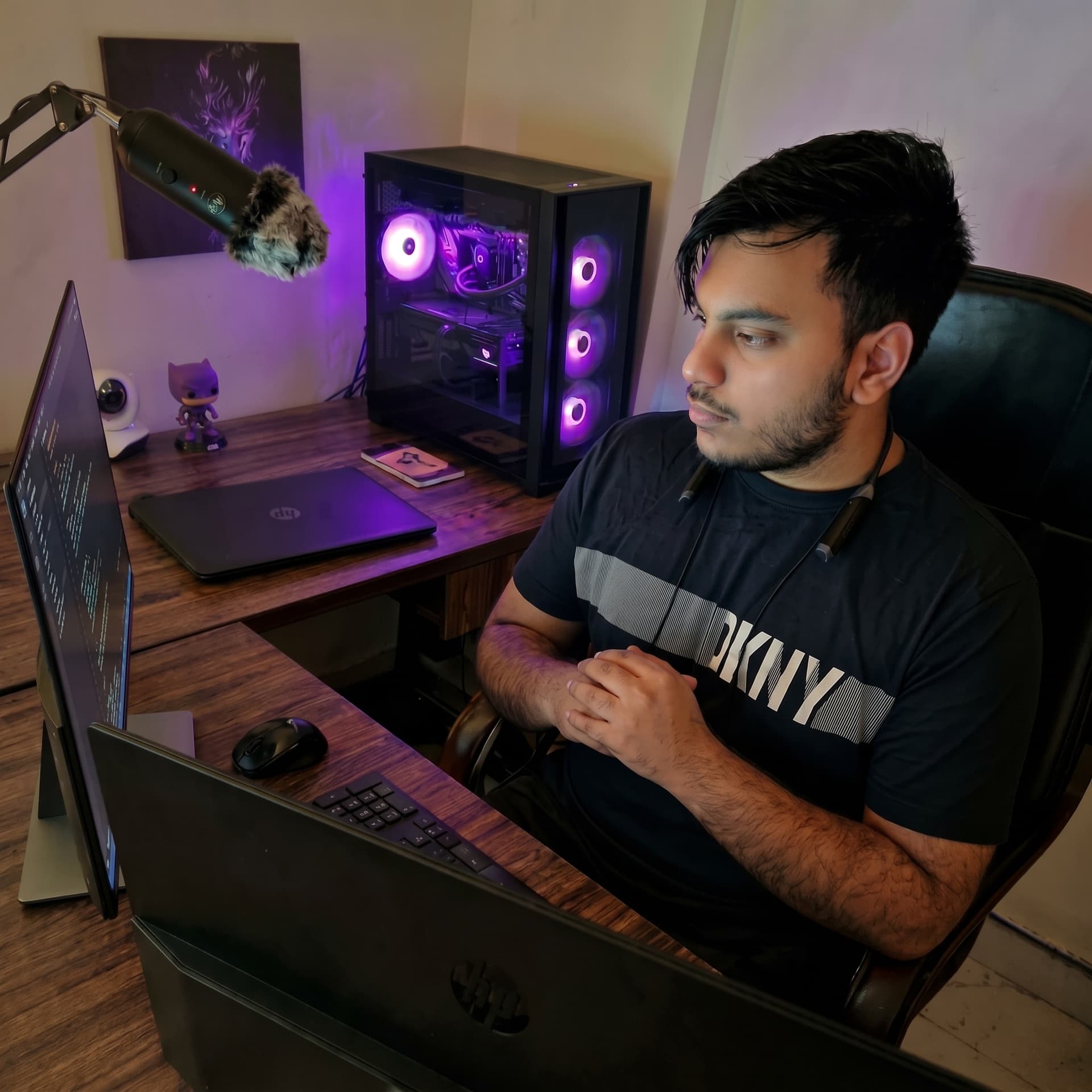 Hamza Ahmad Aslam working at his desk beside a violet-lit computer